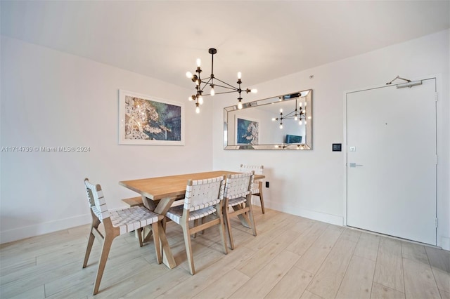 dining space with light hardwood / wood-style floors and a notable chandelier