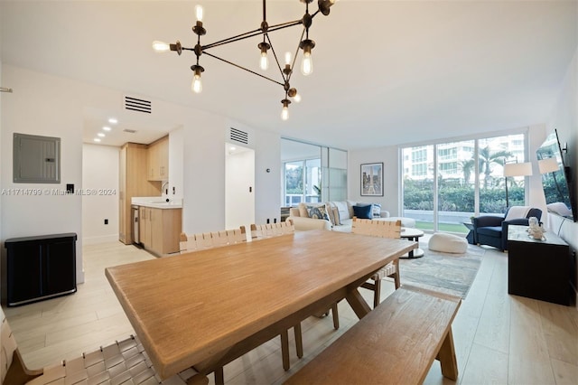 dining area featuring electric panel, an inviting chandelier, a wall of windows, and light hardwood / wood-style flooring