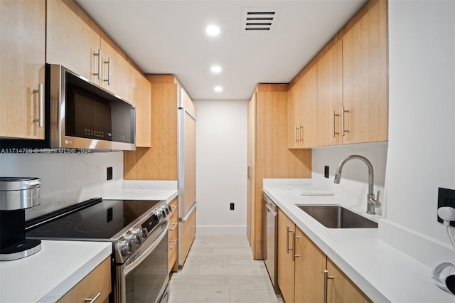 kitchen featuring light brown cabinetry, sink, light hardwood / wood-style flooring, and appliances with stainless steel finishes