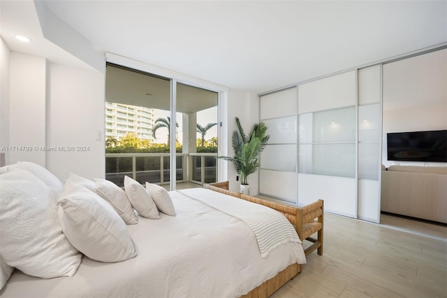 bedroom with light hardwood / wood-style floors and floor to ceiling windows