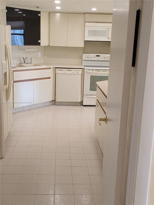 kitchen featuring light tile patterned floors, white appliances, and sink