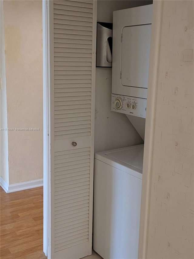 washroom with light hardwood / wood-style floors and stacked washer and clothes dryer