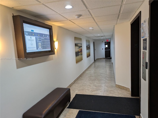 hall with a drop ceiling and light tile patterned floors