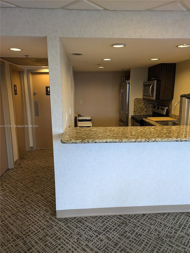 kitchen with sink, decorative backsplash, light stone countertops, kitchen peninsula, and stainless steel appliances