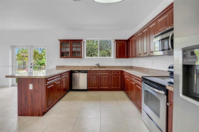 kitchen with kitchen peninsula, appliances with stainless steel finishes, plenty of natural light, and light stone counters