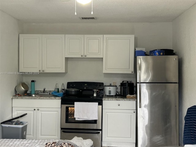 kitchen featuring white cabinetry, sink, stainless steel appliances, and a textured ceiling