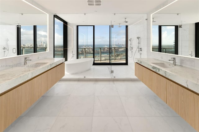 bathroom with vanity, a wealth of natural light, a water view, and independent shower and bath