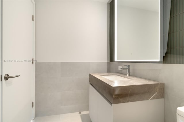 bathroom featuring vanity, toilet, and tile walls