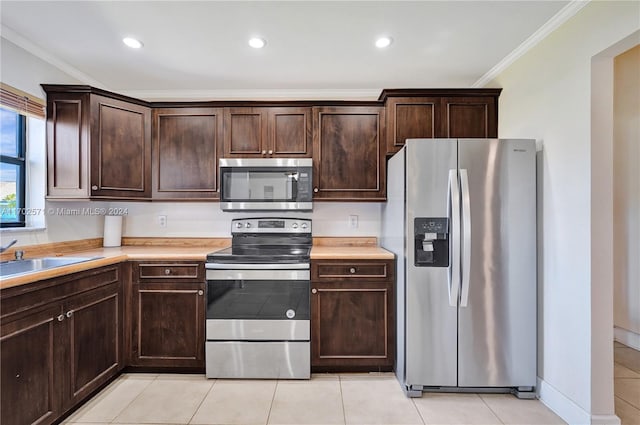 kitchen featuring dark brown cabinetry, sink, appliances with stainless steel finishes, light tile patterned floors, and ornamental molding