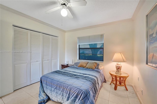 tiled bedroom with ceiling fan, a closet, a textured ceiling, and ornamental molding