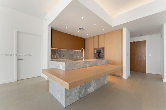 kitchen featuring backsplash, kitchen peninsula, sink, and double oven