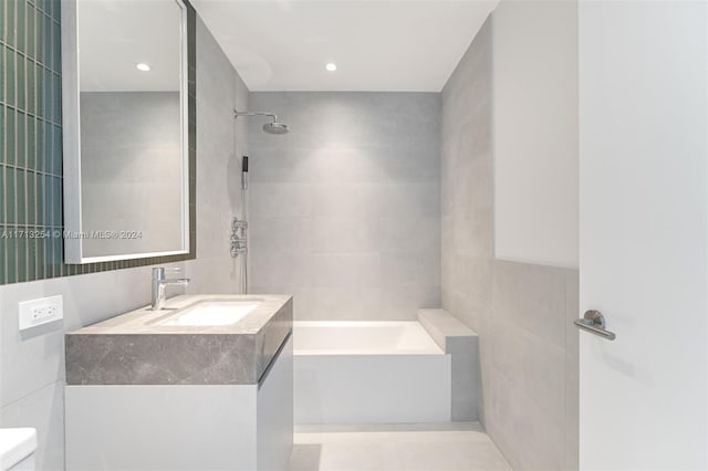 full bathroom with vanity, toilet, tile walls, and tiled shower / bath combo