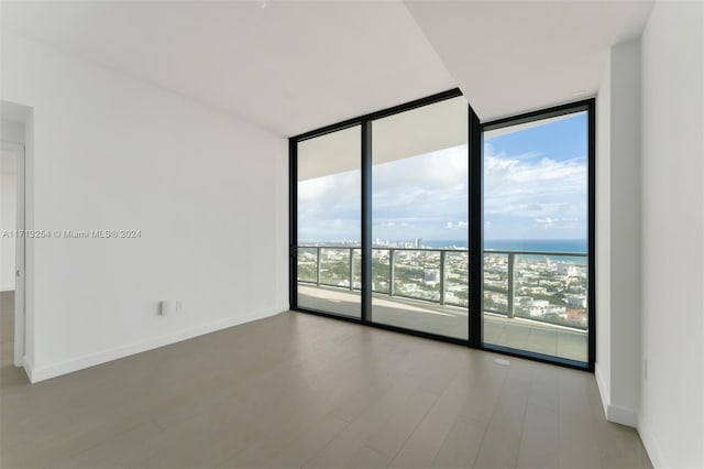 empty room featuring hardwood / wood-style floors, a water view, a wall of windows, and a wealth of natural light