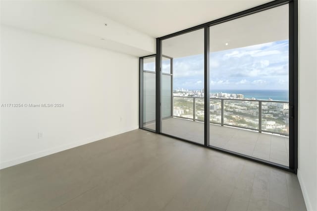 empty room with expansive windows, a water view, and light hardwood / wood-style flooring