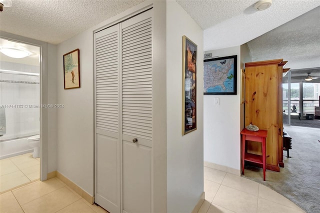 corridor with light tile patterned floors and a textured ceiling