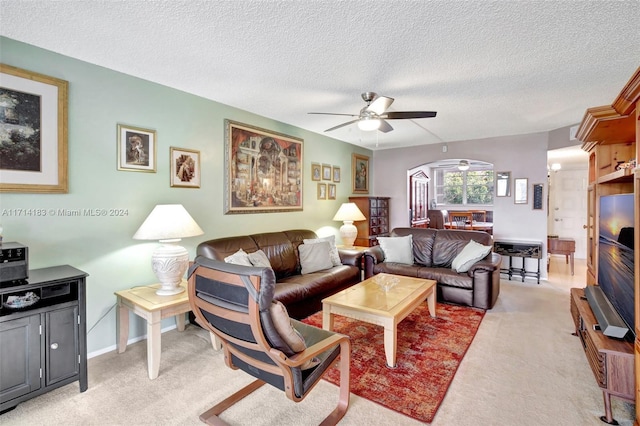 living room with ceiling fan, light colored carpet, and a textured ceiling