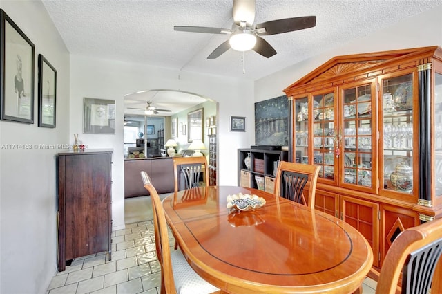 tiled dining space with a textured ceiling and ceiling fan