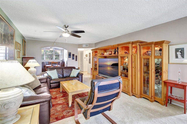 carpeted living room with ceiling fan and a textured ceiling