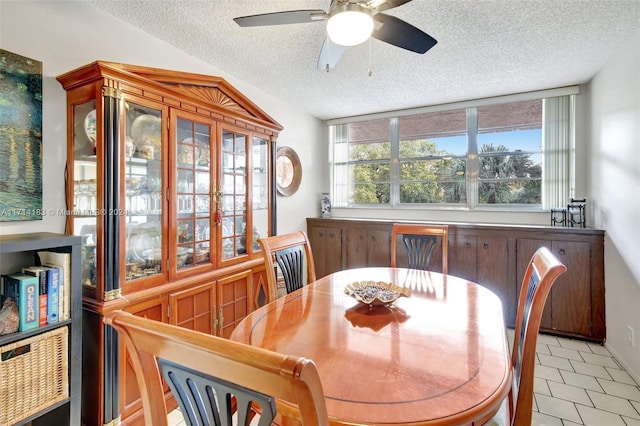 tiled dining space featuring a textured ceiling, vaulted ceiling, and ceiling fan