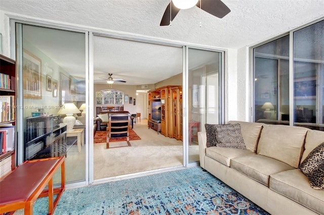 carpeted living room featuring ceiling fan and a textured ceiling