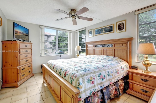 bedroom with ceiling fan, light tile patterned floors, and a textured ceiling