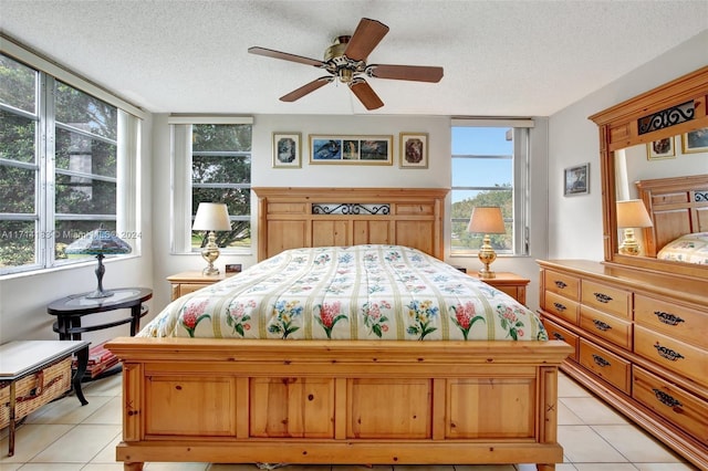 bedroom featuring ceiling fan, light tile patterned floors, and a textured ceiling