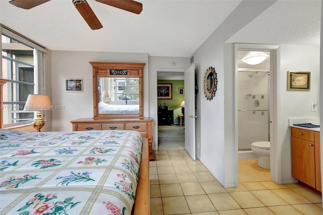 bedroom featuring ceiling fan, light tile patterned flooring, ensuite bathroom, and a textured ceiling