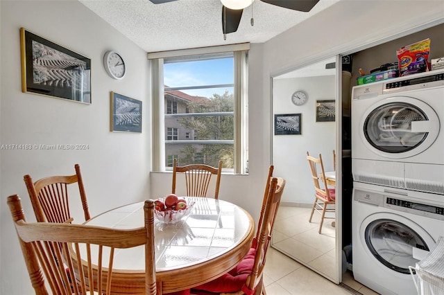 washroom with ceiling fan, light tile patterned flooring, stacked washing maching and dryer, and a textured ceiling