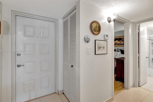 hall featuring light tile patterned floors and a textured ceiling