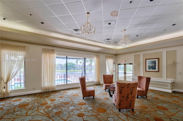 interior space featuring a raised ceiling, plenty of natural light, and a notable chandelier