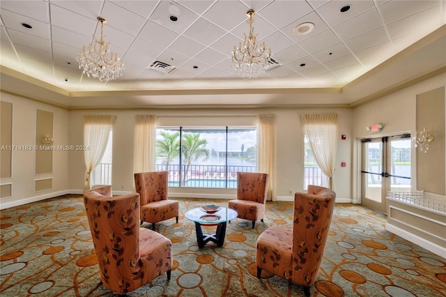 living room with a notable chandelier, french doors, and a tray ceiling