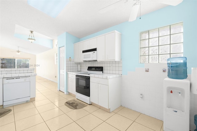 kitchen featuring white cabinets, light tile patterned flooring, white appliances, and vaulted ceiling