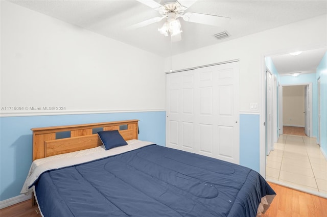 bedroom with a textured ceiling, light wood-type flooring, a closet, and ceiling fan