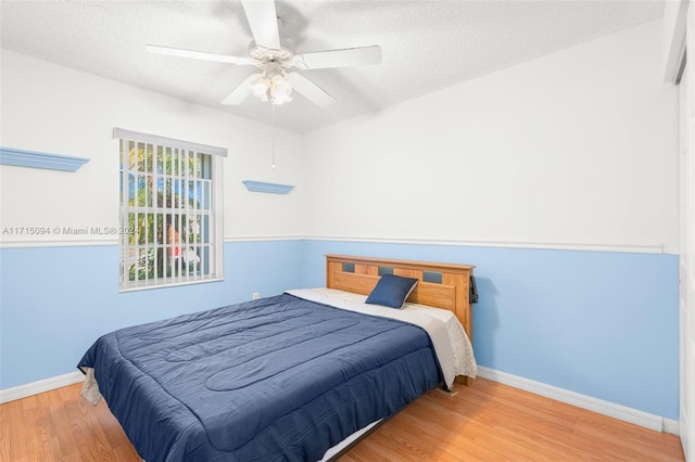 bedroom with ceiling fan, a textured ceiling, and hardwood / wood-style flooring