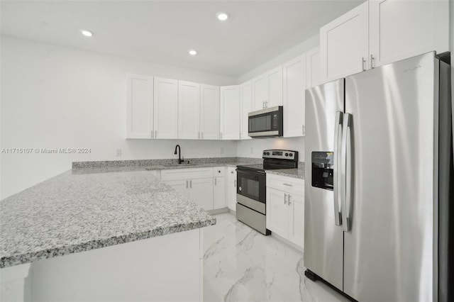 kitchen featuring light stone countertops, sink, stainless steel appliances, kitchen peninsula, and white cabinets