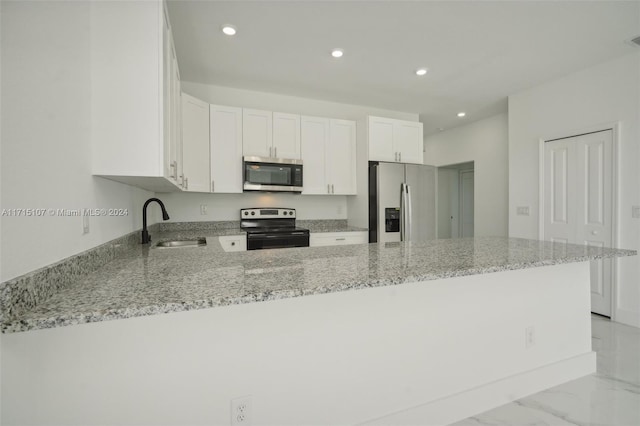 kitchen with white cabinetry, kitchen peninsula, light stone countertops, and stainless steel appliances