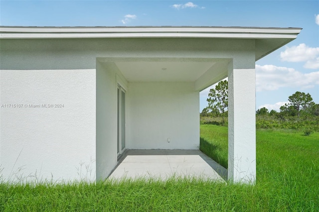 entrance to property with a patio and a lawn