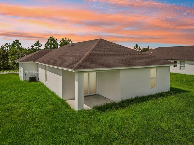 property exterior at dusk featuring cooling unit, a yard, and a patio