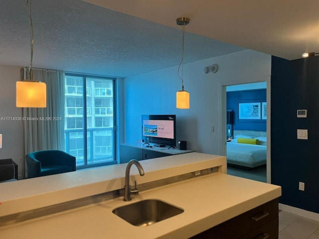 kitchen with light tile patterned floors, a textured ceiling, hanging light fixtures, and sink