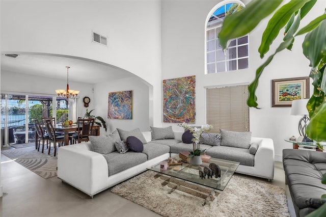 living room featuring a towering ceiling, a water view, and a notable chandelier