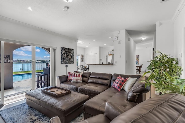 living room with a textured ceiling, a water view, and crown molding