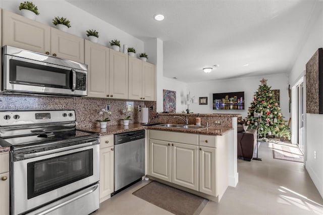 kitchen featuring sink, tasteful backsplash, kitchen peninsula, dark stone countertops, and appliances with stainless steel finishes