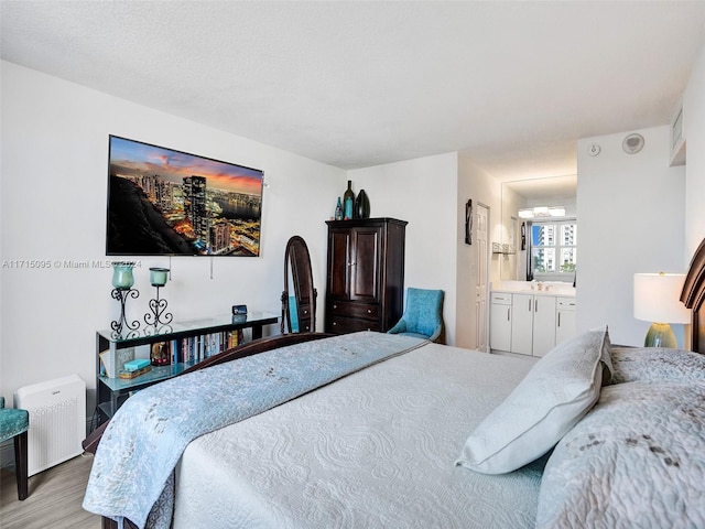 bedroom with ensuite bathroom, light hardwood / wood-style flooring, and radiator