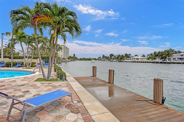 view of dock featuring a fenced in pool, a water view, and a patio