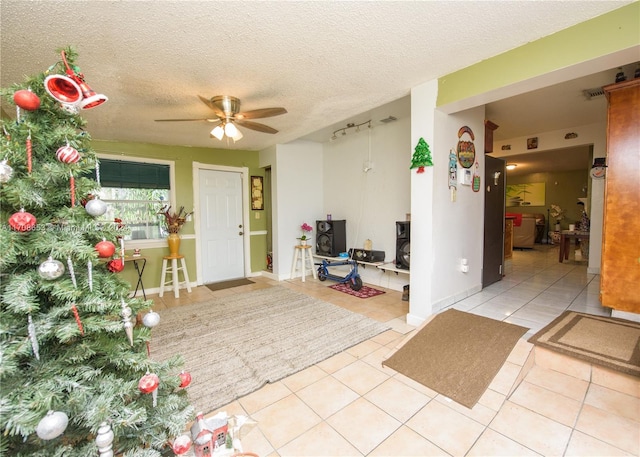 tiled foyer entrance with ceiling fan and a textured ceiling