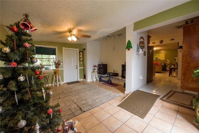 foyer entrance featuring a textured ceiling, ceiling fan, and light tile patterned flooring