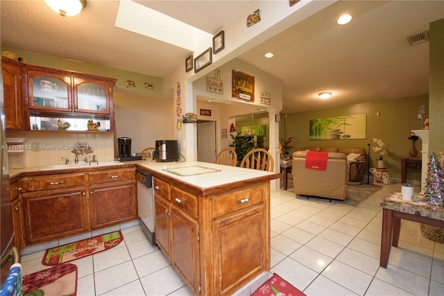 kitchen with sink, backsplash, kitchen peninsula, white dishwasher, and light tile patterned flooring