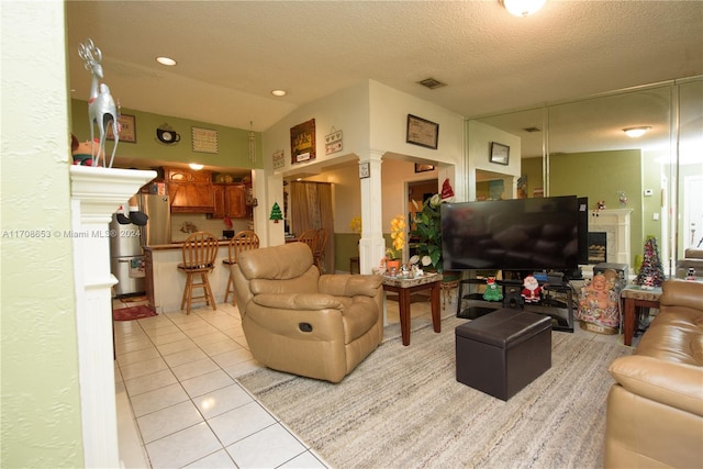 living room featuring a textured ceiling, decorative columns, lofted ceiling, and light tile patterned flooring