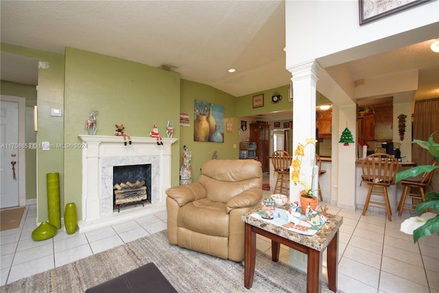 living room featuring light tile patterned flooring, ornate columns, a premium fireplace, and vaulted ceiling