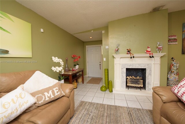 living room featuring a fireplace, light tile patterned flooring, and a textured ceiling